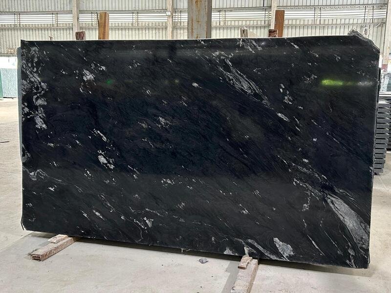 Dalle de granit Noir Océan avec des stries blanches et grises fluides sur un fond sombre